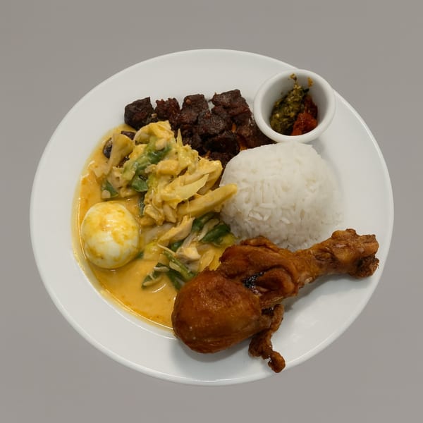Indonesian dish with fried chicken, rice, beef rendang, egg, and vegetables in a yellow curry sauce.
