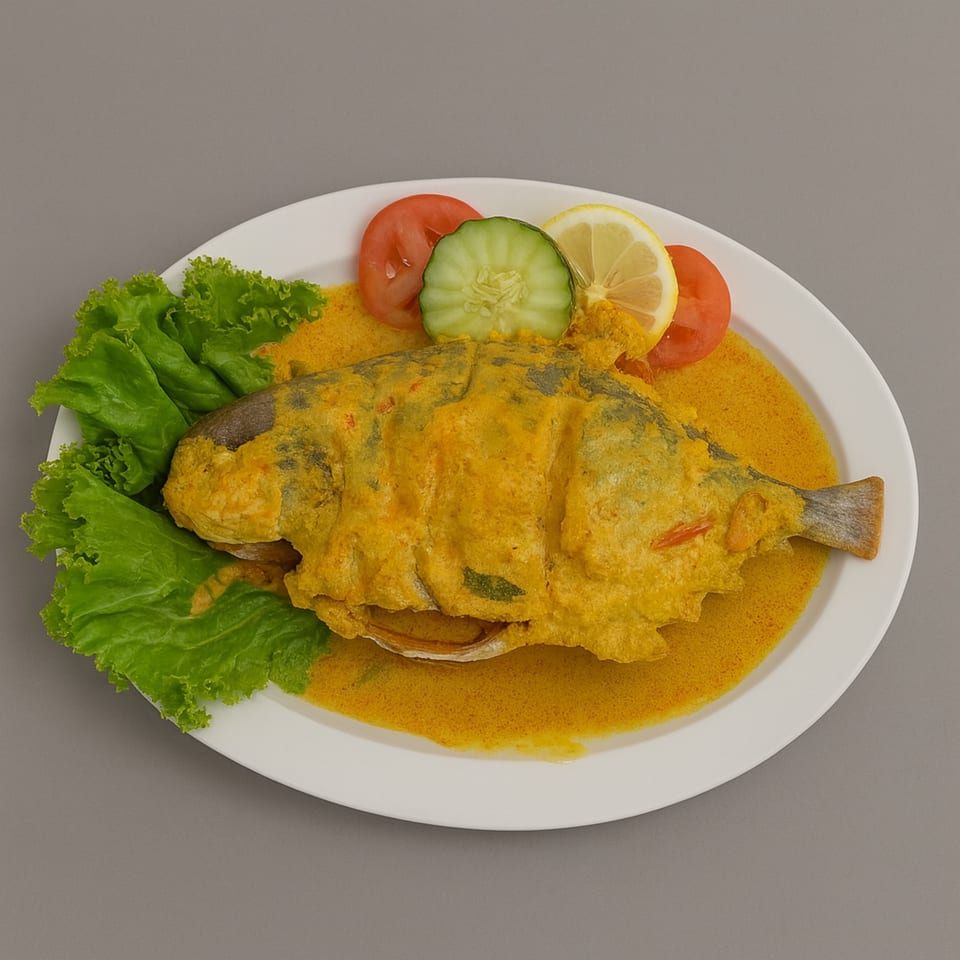 Indonesian whole fish in yellow curry sauce, garnished with lettuce, tomato, cucumber, and lemon.