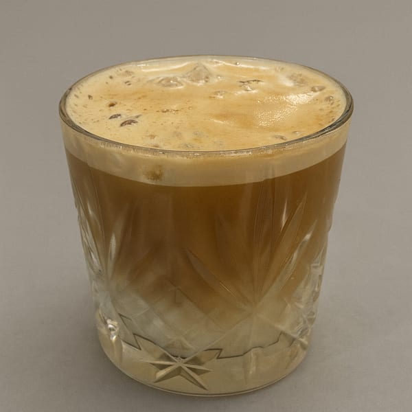 Iced coffee with foam in a textured glass, a refreshing drink from RENDANG & CO.