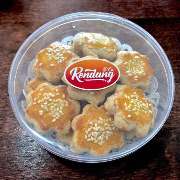 Star-shaped Rendang & Co cookies with sesame seeds in a clear plastic container.