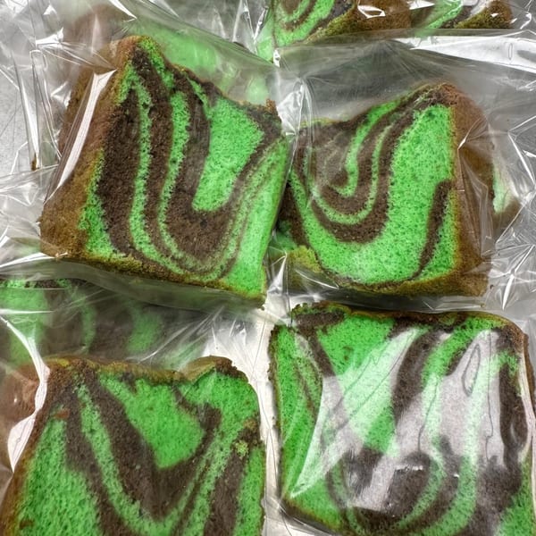 Several slices of green and brown marbled cake, individually wrapped in clear plastic.