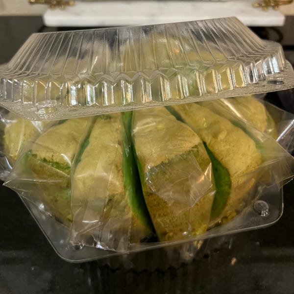 Indonesian pastries, wrapped in plastic, inside a clear plastic container, ready for takeaway.