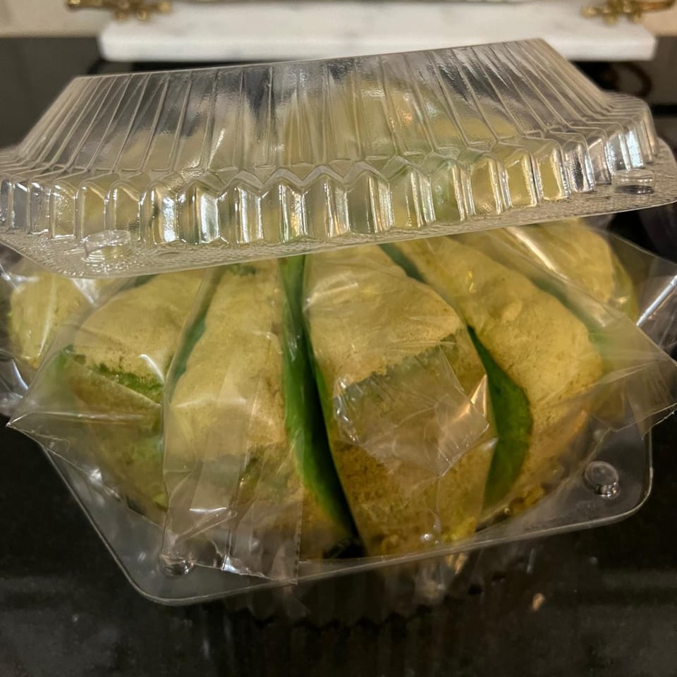 Indonesian pastries, wrapped in plastic, inside a clear plastic container, ready for takeaway.