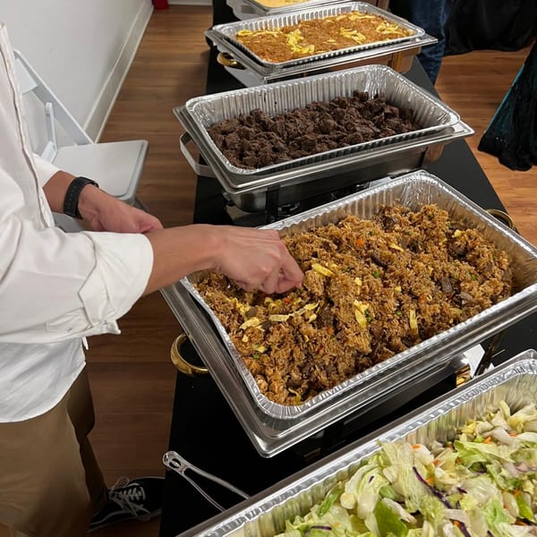 A person serving themselves Rendang & Co's Indonesian fried rice from a buffet line.