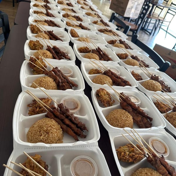 Rows of Indonesian take-out containers filled with satay skewers, rice, and fried snacks.