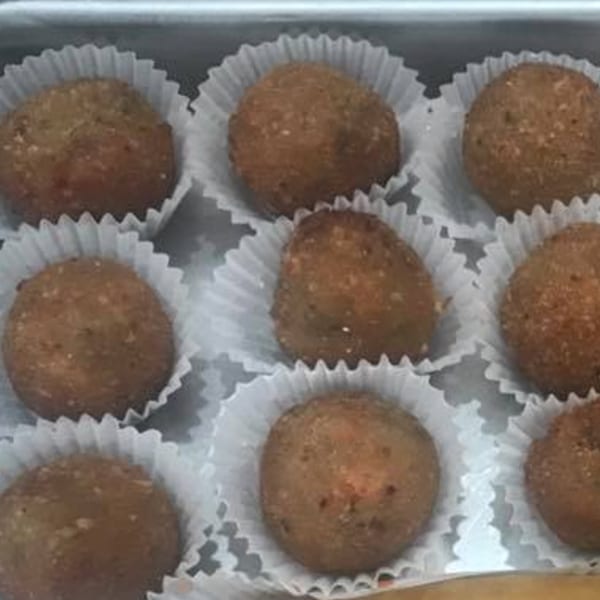 Nine brown, round Indonesian snacks in white paper cups, arranged in rows.