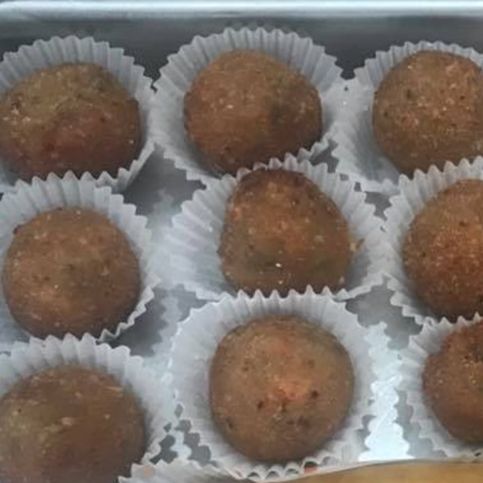Nine brown, round Indonesian snacks in white paper cups, arranged in rows.