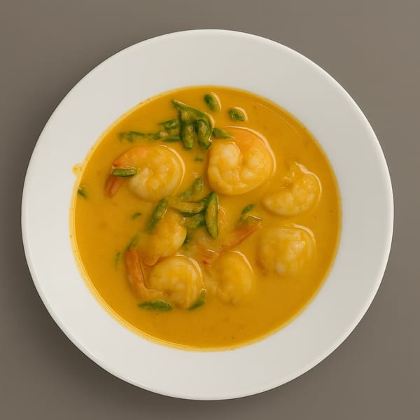 A white bowl filled with vibrant orange shrimp curry and green beans, from RENDANG & CO.