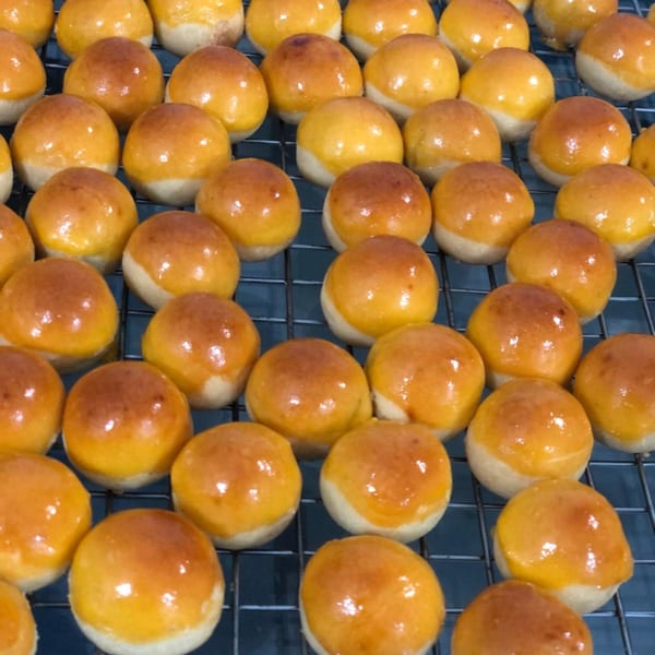 Rows of golden-brown Indonesian pineapple tarts, or Nastar, cooling on a wire rack.