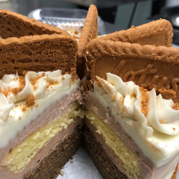 Two slices of layered cake with white frosting and Lotus Biscoff cookies on top.