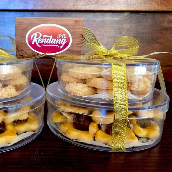 Rendang & Co. Indonesian Bistro cookies in clear containers with gold ribbons and a logo.