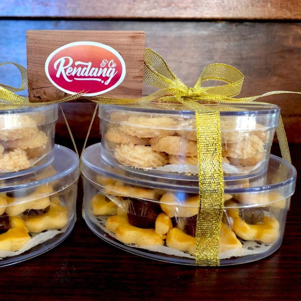 Rendang & Co. Indonesian Bistro cookies in clear containers with gold ribbons and a logo.