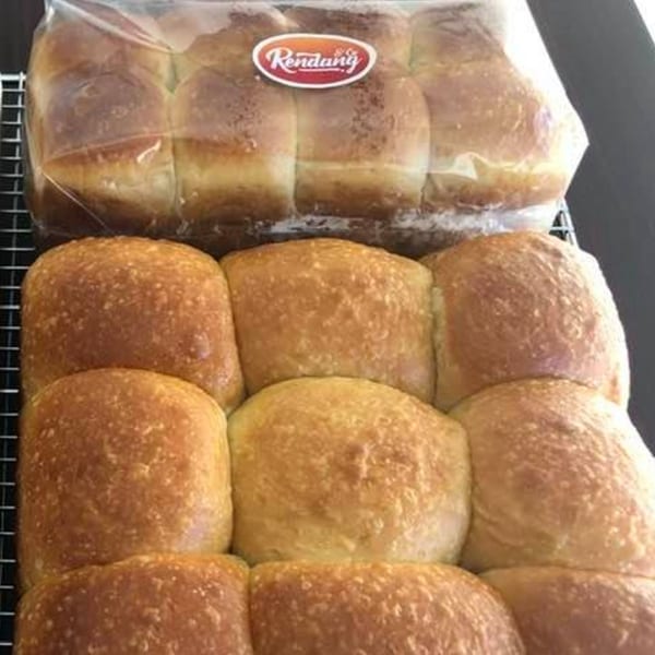 Freshly baked Rendang & Co. buns, some packaged and some arranged on a cooling rack.