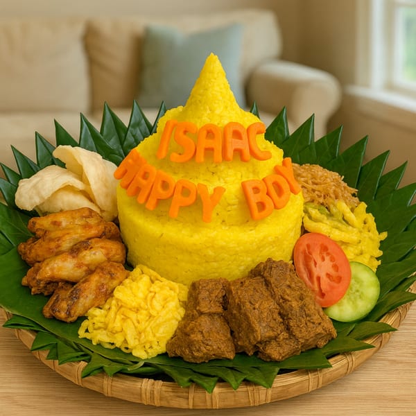 Indonesian Tumpeng rice cone with "Isaac Happy Boy" text, chicken wings, rendang, and vegetables.